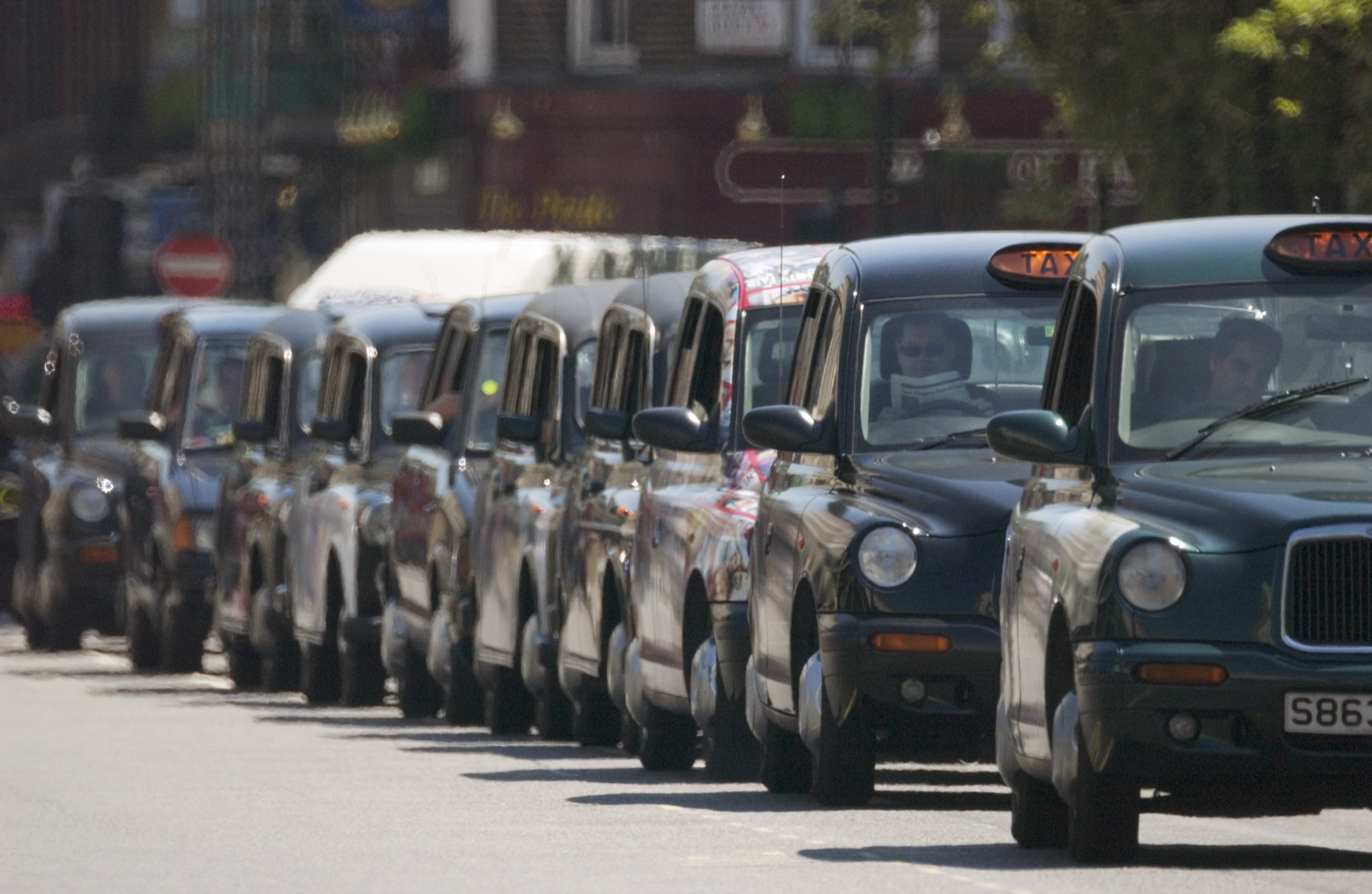 A row of black taxis parked on the side of the road